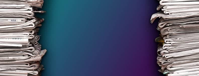 Stacks of newspapers sit against a blue wall.