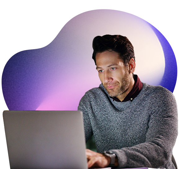 A man wearing a grey jumper works intently on a laptop