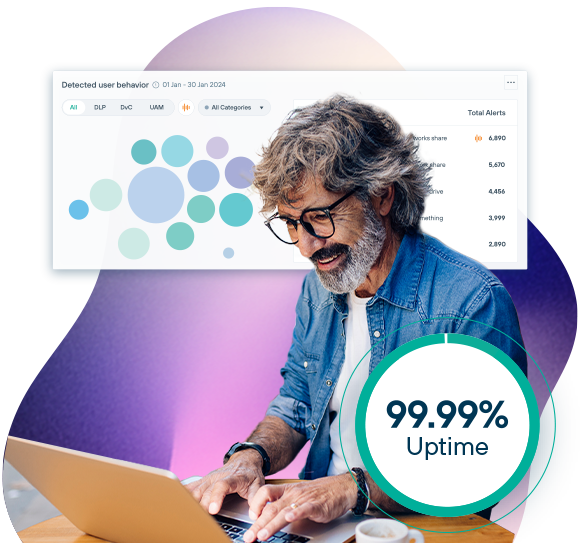 A grey-haired, bespectacled man looks happy as he works on a laptop.