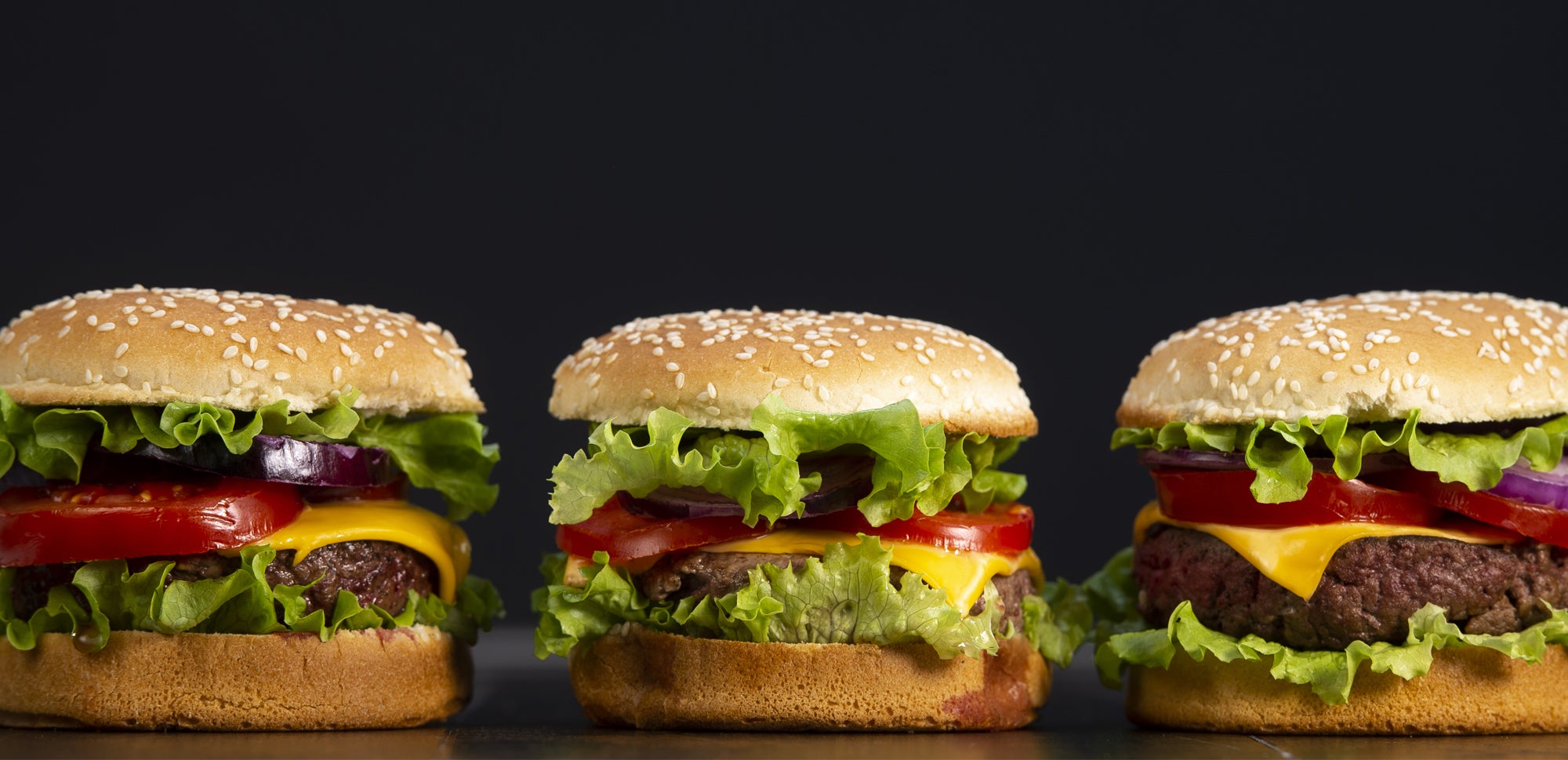 Three large burgers with several layers of fillings each